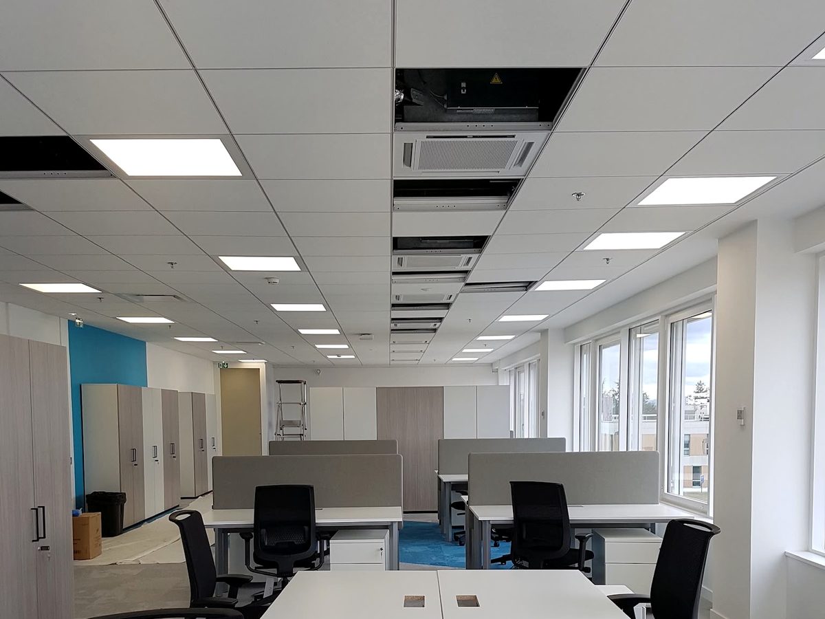 Open space livré : faux plafond à dalles, cloisons, revêtement de sol et postes de travail installés.